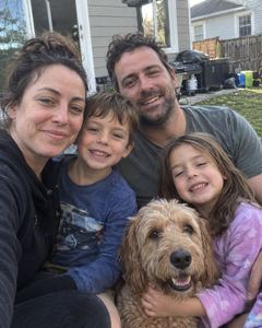 Example phone photo: a selfie of a family of four and their curly-haired dog in a back garden