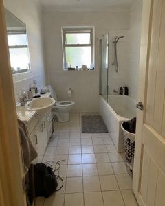 Example phone photo: a plain white-tiled bathroom with clutter on the floor