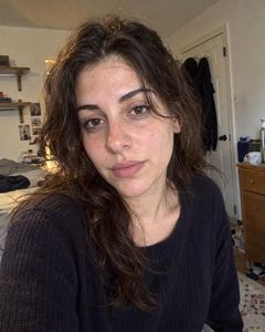 Example phone photo: a selfie of a woman with long dark hair in a navy sweater in her bedroom