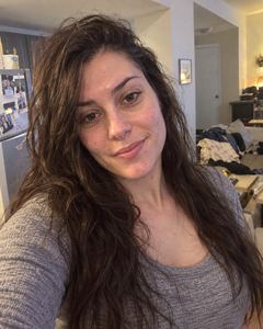 Example phone photo: a selfie of a woman with long dark hair in a messy bedroom