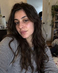 Example phone photo: a selfie of a woman with long dark hair in a grey top in her bedroom