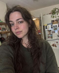 Example phone photo: a selfie of a woman with long dark hair in a green sweater in her kitchen