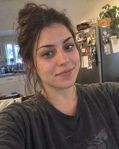 Example phone photo: a selfie of a woman with her hair up in a grey T-shirt in her kitchen